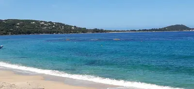 a view of a beach with blue water and a mountain at studio 5min plage agosta in Albitreccia