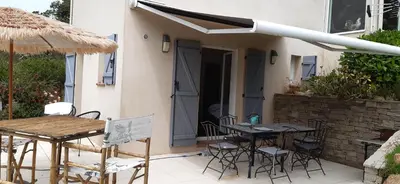 a patio with tables and chairs and an umbrella at studio 5min plage agosta in Albitreccia