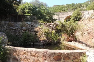 a stone wall with a pond in front of a bridge at L'Ortu Di Pisettu -2 in Conca