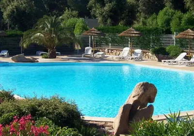 a large blue swimming pool with chairs and umbrellas at Vacances en Chalet ou Mobil-home chez Camp'in Pirellu in Porto-Vecchio