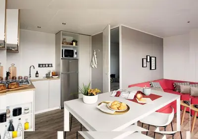 a kitchen and living room with a white table at Vacances en Chalet ou Mobil-home chez Camp'in Pirellu in Porto-Vecchio