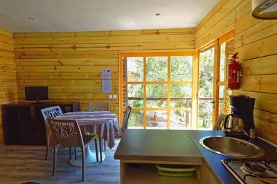 a kitchen with a table and a dining room at Vacances en Chalet ou Mobil-home chez Camp'in Pirellu in Porto-Vecchio