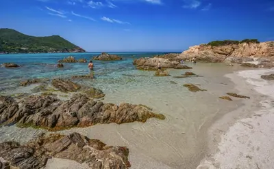 a beach with rocks and people in the water at Toit Terrasse centre historique in Ajaccio