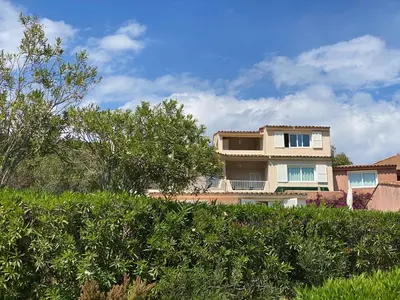 a house with a hedge in front of a building at Santa Giulia - Le village de L'hacienda in Porto-Vecchio