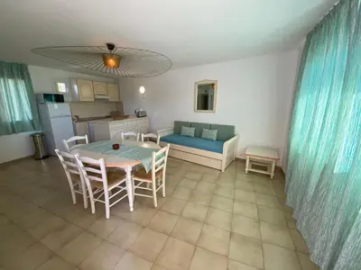 a kitchen and living room with a table and chairs at Santa Giulia - Le village de L'hacienda in Porto-Vecchio