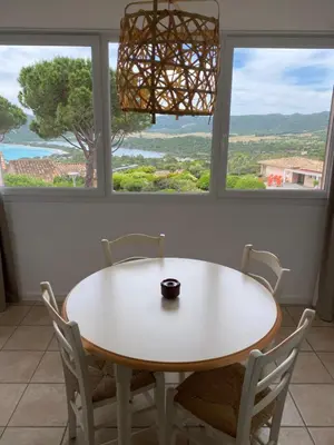 a table and chairs in a room with two windows at Santa Giulia - Le village de L'hacienda in Porto-Vecchio