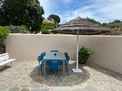 a table with chairs and an umbrella on a patio at Santa Giulia - Le village de L'hacienda in Porto-Vecchio