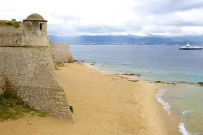 a beach next to the ocean with a cruise ship at T2 type new yorkais in Ajaccio