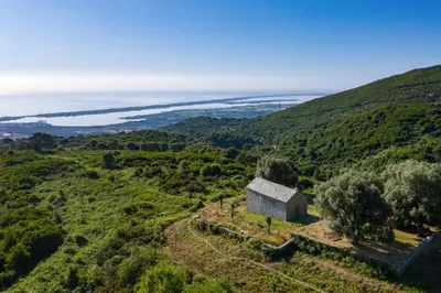 an old house on a hill with the ocean in the background at Appartement neuf entre mer et montagne. in Furiani