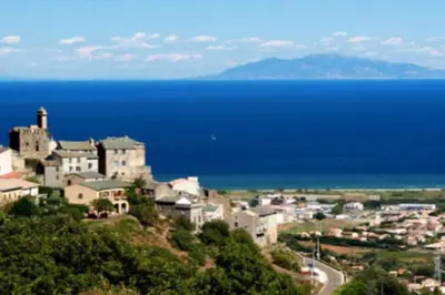a town on a hill with the ocean in the background at Appartement neuf entre mer et montagne. in Furiani