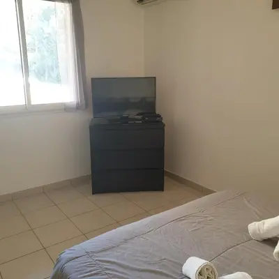 a bedroom with a flat screen tv and a bed at Appart RDC ALZETU CLIMATISE - 2 MIN PLAGE - PISCINE in Lecci