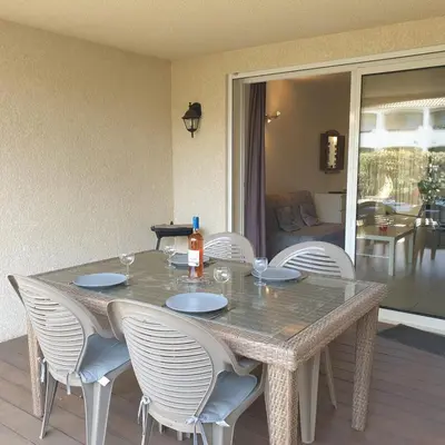 a dining room table with chairs and a bottle of wine on it at Appart RDC ALZETU CLIMATISE - 2 MIN PLAGE - PISCINE in Lecci