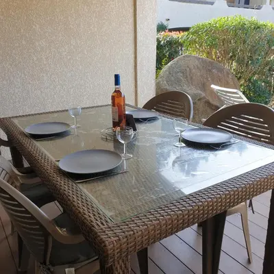 a table with plates and a bottle of wine on it at Appart RDC ALZETU CLIMATISE - 2 MIN PLAGE - PISCINE in Lecci