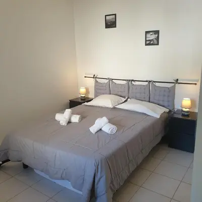 a bedroom with a large bed with towels on it at Appart RDC ALZETU CLIMATISE - 2 MIN PLAGE - PISCINE in Lecci