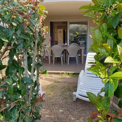 a patio with a table and chairs in the yard at Appart RDC ALZETU CLIMATISE - 2 MIN PLAGE - PISCINE in Lecci