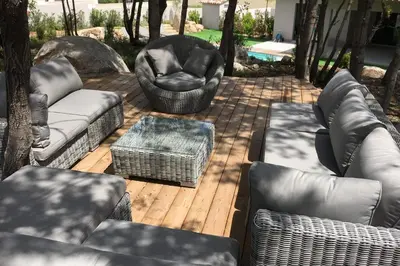 a patio with couches and chairs on a wooden deck at Villa Tinuta 8 pers piscine chauffée 5 min plage en voiture in Sainte-Lucie de Porto-Vecchio