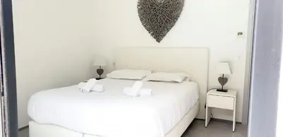 a white bedroom with a white bed with two pillows at Villa Tinuta 8 pers piscine chauffée 5 min plage en voiture in Sainte-Lucie de Porto-Vecchio