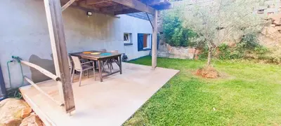 a patio with a table and chairs in a yard at Appt Bruscaghju 6 pers 10 min rivière à pieds xx 15 min plage en voiture in Sainte-Lucie de Porto-Vecchio