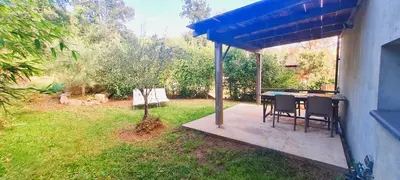 a patio with a table and chairs in a yard at Appt Bruscaghju 6 pers 10 min rivière à pieds xx 15 min plage en voiture in Sainte-Lucie de Porto-Vecchio