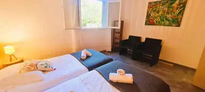 a bedroom with two beds and a window and a chair at Appt Bruscaghju 6 pers 10 min rivière à pieds xx 15 min plage en voiture in Sainte-Lucie de Porto-Vecchio
