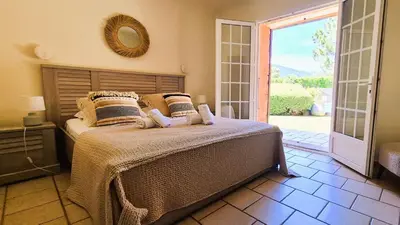 a bedroom with a bed and a door to a patio at Villa Lucendiluna 10 personnes piscine 5 min plage en voiture in Sainte-Lucie de Porto-Vecchio