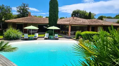a swimming pool in front of a house with umbrellas at Villa Lucendiluna 10 personnes piscine 5 min plage en voiture in Sainte-Lucie de Porto-Vecchio