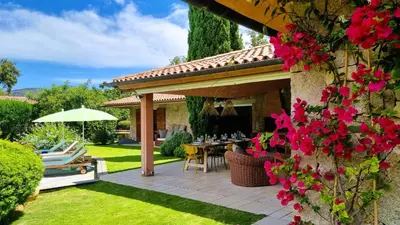 a garden with a patio with a table and flowers at Villa Lucendiluna 10 personnes piscine 5 min plage en voiture in Sainte-Lucie de Porto-Vecchio