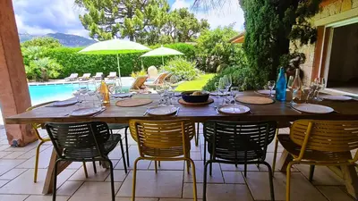 a large wooden table with chairs and a pool at Villa Lucendiluna 10 personnes piscine 5 min plage en voiture in Sainte-Lucie de Porto-Vecchio