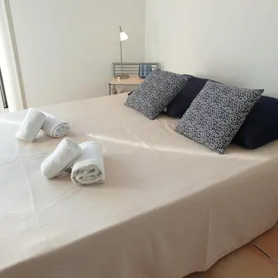 a white bed with towels and pillows on it at Mini villa Messicana 5 pers piscine 500 m plage in Lecci