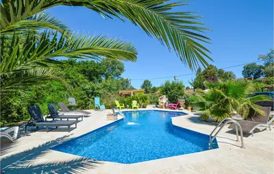 a swimming pool in a yard with chairs and trees at Awesome Home In Petreto Bicchisano in Petreto-Bicchisano