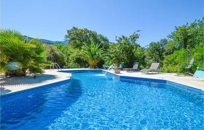 a blue swimming pool with chairs and trees at Awesome Home In Petreto Bicchisano in Petreto-Bicchisano