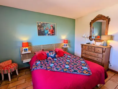a bedroom with a red bed and a dresser and a mirror at La villa Acacia in Coti-Chiavari