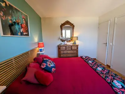 a bedroom with a large red bed with a red blanket at La villa Acacia in Coti-Chiavari