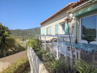 a house with a table and chairs on a balcony at La villa Acacia in Coti-Chiavari