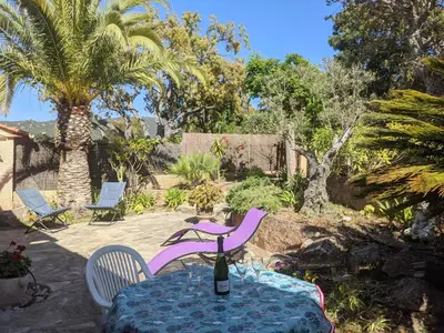 a table and chairs with a bottle of wine on it at La villa Acacia in Coti-Chiavari