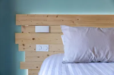 a bed with a wooden headboard and a white pillow at Porticcio - T2 neuf à 5min à pieds de la plage in Porticcio