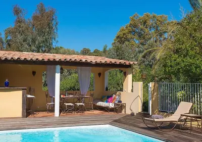 a woman sitting on a deck next to a swimming pool at Villa RUSCANA AVEC PISCINE PRIVÉE in Sainte-Lucie de Porto-Vecchio
