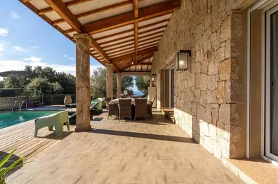 an outdoor patio with a wooden roof and a pool at Villa vue mer 4 chambres in Olmeto
