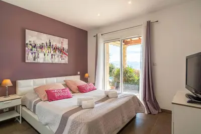 a bedroom with a bed with pink pillows and a window at Villa vue mer 4 chambres in Olmeto