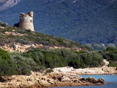 a castle on a hill next to a body of water at Villa piscine Sagone Paradise avec magnifique vue mer in Sagone