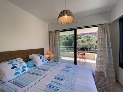a bedroom with a bed with a view of a balcony at Coté Plage pied dans l'eau vue mer in Propriano