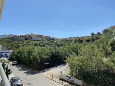 a view of a beach with trees and a building at Coté Plage pied dans l'eau vue mer in Propriano
