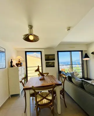 a living room with a table and a couch at Coté Plage pied dans l'eau vue mer in Propriano
