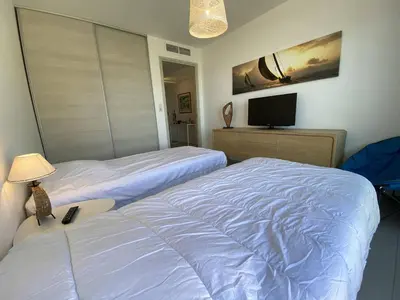 a bedroom with two beds and a tv in it at Coté Plage pied dans l'eau vue mer in Propriano