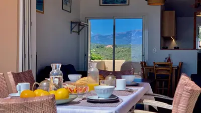 a dining room table with a plate of fruit on it at Maison 4 pièces, vue panoramique, piscine, climatisation, près de Palombaggia in Porto-Vecchio
