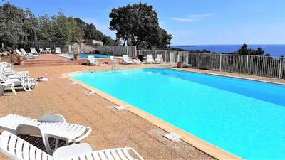 a swimming pool with white lounge chairs and a swimming pool at Maison 4 pièces, vue panoramique, piscine, climatisation, près de Palombaggia in Porto-Vecchio