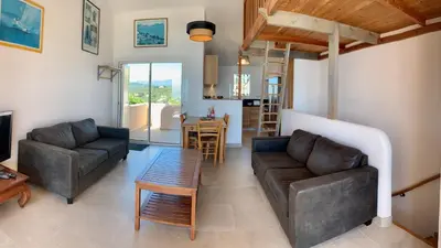 a living room with two couches and a table at Maison 4 pièces, vue panoramique, piscine, climatisation, près de Palombaggia in Porto-Vecchio