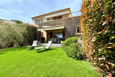 a yard with two chairs and a house at Appartement Les Hameaux de Pinarello in Sainte-Lucie de Porto-Vecchio
