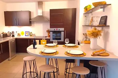 a kitchen with a table and stools in a kitchen at Appartement Les Hameaux de Pinarello in Sainte-Lucie de Porto-Vecchio