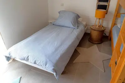 a small bedroom with a bed with a blue comforter at Appartement Les Hameaux de Pinarello in Sainte-Lucie de Porto-Vecchio